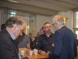 Mannen praten met drankje aan tafel.