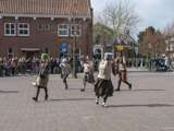 Verklede mensen spelen toneelstuk op kerkplein bij Living History Appingedam. Ze hebben pannen op hun hoofd.