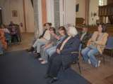 Mensen zitten op bankjes in de kerk en luisteren.