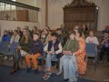 Mensen zitten op bankjes in de kerk en luisteren.