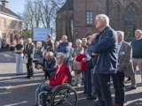 Mensen kijken naar het citatenbord op het kerkplein van Appingedam.