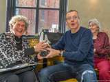 Vrouw overhandigt de Pelikaan-prijs aan man. Ze glimlachen naar de camera.