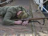 Verklede soldaat ligt plat op brug bij Living History Appingedam.