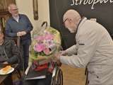 Vrouw overhandigt een boeket bloemen aan Jan Dijkhuizen.
