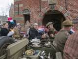 Verklede mensen met oude auto en Nederlandse vlaggen in hand op kerkplein bij Living History Appingedam.