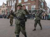 Verklede soldaten op kerkplein bij Living History, Appingedam, houden geweren in de lucht.