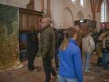 Mensen staan in de kerk en bekijken de kunstwerken.