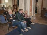 Mensen zitten op bankjes in de kerk en luisteren.