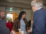 Mensen praten aan tafels en drinken koffie in gemeenschappelijke ruimte.