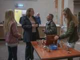 Mensen staan in de kerk rond tafeltjes te praten.