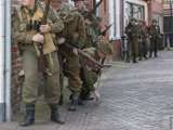 Groep verklede soldaten schuilen achter muur bij Living History Appingedam.