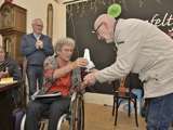 Vrouw overhandigt de Pelikaan-prijs aan Jan Dijkhuizen. Beide glimlachen.