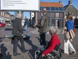 Twee mannen en twee vrouwen kijken naar het citatenbord op het kerkplein in Appingedam.