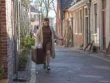 Vrouw met koffer loopt door straat bij Living History Appingedam.
