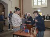 Mensen staan in de kerk rond tafeltjes te praten.