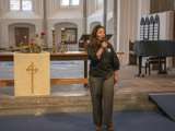 Vrouw spreekt in microfoon in de kerk.