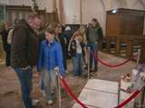 Mensen staan in de kerk en bekijken de kunstwerken.