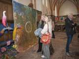 Mensen staan in de kerk en bekijken de kunstwerken.