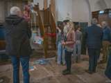 Mensen staan in de kerk en bekijken de kunstwerken.
