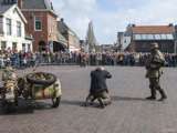 Verklede mensen spelen een toneelstuk op kerkplein bij Living History Appingedam. Soldaar houdt vluchteling onder vuur.