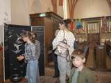 Mensen staan in de kerk en bekijken de kunstwerken.