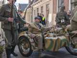 Verklede mensen rijden door straat met oude oorlogsmotor bij Living History Appingedam.