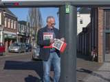 Man staat bij paal van citatenbord met QR-code en platen.