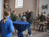 Mensen staan in de kerk rond tafeltjes te praten.