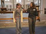 Kind spreekt in microfoon in de kerk. Een vrouw staat ernaast en houdt de microfoon vast.