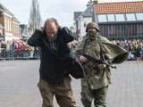 Verklede mensen spelen toneelstuk op kerkplein bij Living History Appingedam. Een soldaat neemt een gevangene mee.