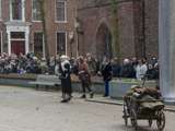 Verklede mensen praten op kerkplein bij Living History Appingedam. Er staat ook een oude wagen.