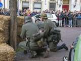 Verklede soldaten spelen toneelstuk op kerkplein en verstoppen zich after een hooibaal bij Living History Appingedam.