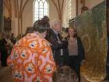 Mensen staan in de kerk en bekijken de kunstwerken.