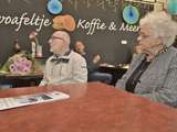 Jan Dijkhuizen en een vrouw zitten bij koffiebar 't Stroopwafeltje.