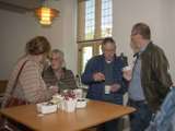 Mensen praten gezellig rondom tafel met koffie. 