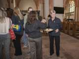Vrouw deelt hapjes uit in de kerk bij de kunstwerken.