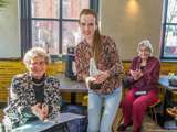 Vrouw glimlacht naast andere vrouw terwijl ze de Pelikaan-prijs vasthoudt.