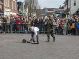 Verklede mensen praten op kerkplein bij Living History Appingedam. Één van de mannen pakt een laars op.