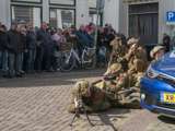 Verklede soldaten liggen op grond en verstoppen zich achter auto bij Living History Appingedam.