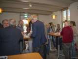 Mensen praten aan tafels en drinken koffie in gemeenschappelijke ruimte.