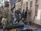 Verklede mensen spelen een toneelstuk bij Living History Appingedam. Mensen staan met hun gezicht naar een muur.