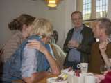 Mensen praten aan tafels en drinken koffie in gemeenschappelijke ruimte.